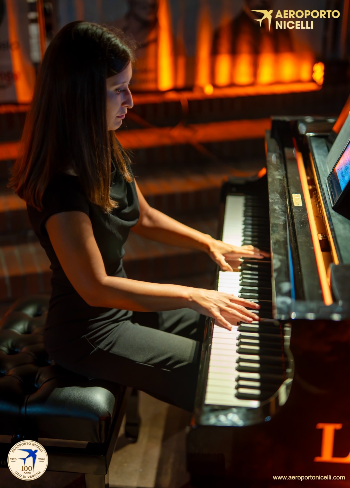 Una donna seduta al pianoforte mentre suona, con sfondo luminoso e suggestivo.